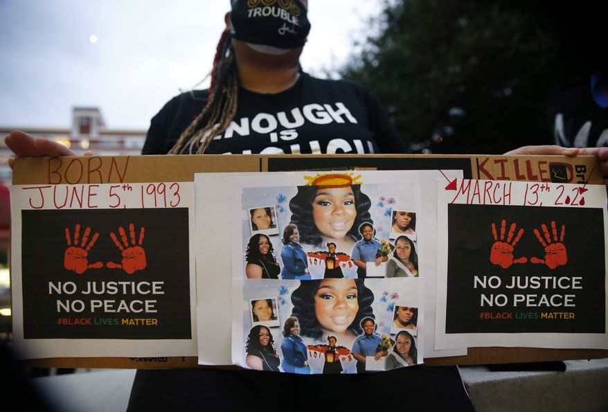Shena Lee of Dallas displays photos of Breonna Taylor during a Next Generation Action Network protest outside of Dallas Police Headquarters before they marched down S. Lamar St. in Dallas, Wednesday, Sept. 23, 2020. A Kentucky grand jury brought no charges against the Louisville police for the killing of Taylor during a drug raid gone wrong. (Tom Fox/The Dallas Morning News via AP)