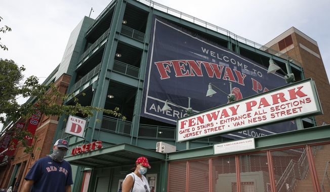 In this July 24, 2020, file photo, two fans walk on a normally crowded Jersey Street in front of Fenway Park before an opening day baseball game between the Boston Red Sox and the Baltimore Orioles. Elections officials in Boston are expected to approve Fenway Park as an early voting venue when they meet on Thursday, Sept. 24, after Red Sox owner John Henry offered the storied ballpark for voters hesitant to cast ballots indoors during the coronavirus pandemic. (AP Photo/Michael Dwyer, File)
