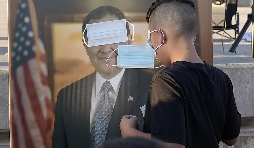 FILE - In this Sept. 5, 2020 file photo, children play "pin the mask on Gov. Gary Herbert" during a "Trash Your Mask Protest" rally hosted by the Utah Business Revival at the Utah State Capitol in Salt Lake City. Herbert will increase pandemic restrictions in two Utah cities. But he stopped short of implementing any mask mandates state officials announced Tuesday, Sept. 22, 2020, as COVID-19 cases continue to surge in the state. (AP Photo/Rick Bowmer, File)