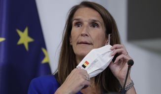 Belgian Prime Minister Sophie Wilmes takes off her protective mask prior to a press conference following the National Security Council meeting on the COVID-19 outbreak, in Brussels, Wednesday, Sept. 23, 2020. Belgium&#39;s prime minister announced Wednesday a relaxation of social-distancing rules as part of a less stringent long-term coronavirus strategy, despite the steady rise of COVID-19 cases in a country already hard-hit by the virus. (Olivier Hoslet, Pool via AP)