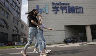 FILE - In this Aug. 7, 2020, file photo, women wearing masks to prevent the spread of the coronavirus chat as they pass by the headquarters of ByteDance, owners of TikTok, in Beijing, China. TikTok&#39;s owner said Thursday, Sept. 24, 2020, that it has applied for a Chinese technology export license as it tries to complete a deal with Oracle and Walmart to keep the popular video app operating in the United States. (AP Photo/Ng Han Guan, File)
