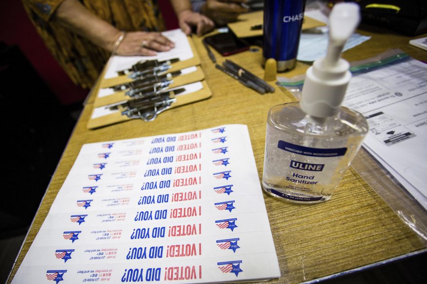 FILE - In this March 17, 2020, file photo, hand sanitizer and stickers are set up at a polling station in Chicago. Election Day voters, whose numbers have waned in recent years because of expanded options for casting ballots, likely will be reduced even further this year with a surge in vote-by-mail popularity during a pandemic. Ballots to those who applied to vote by mail started going out on Thursday, Sept. 24, 2020, to a record 1.82 million voters thus far, according to the Illinois State Board of Elections. Legislation adopted last spring ensured widespread publicity for the practice because of the coronavirus outbreak. ( James Foster/Chicago Sun-Times via AP, File)