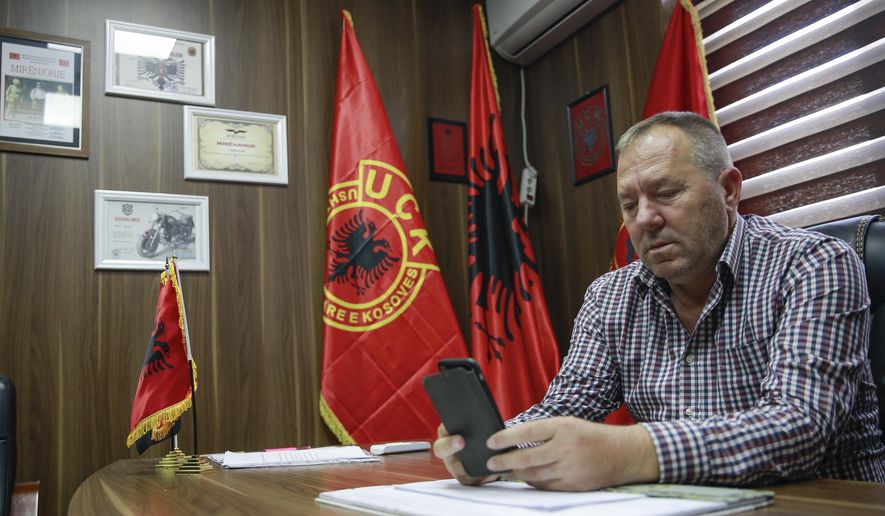 Hysni Gucati head of the War Veterans Organization of the Kosovo Liberation Army looks at a photo of his co-fighter former Kosovo Liberation Army commander Salih Mustafa after news of his arrest, during an interview with The Associated Press, in Pristina, Thursday, Sept. 24, 2020. A special international court said Thursday that a former commander of the separatist fighters in Kosovo's 1998-1999 war has been arrested as part of a war crimes and crimes against humanity probe stemming from the conflict with Serbia. (AP Photo/Visar Kryeziu)