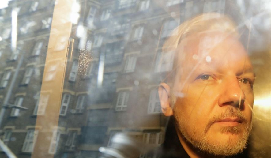 In this Wednesday, May 1, 2019, file photo, buildings are reflected in the window as WikiLeaks founder Julian Assange is taken from court, where he appeared on charges of jumping British bail seven years ago, in London. (AP Photo/Matt Dunham, File)