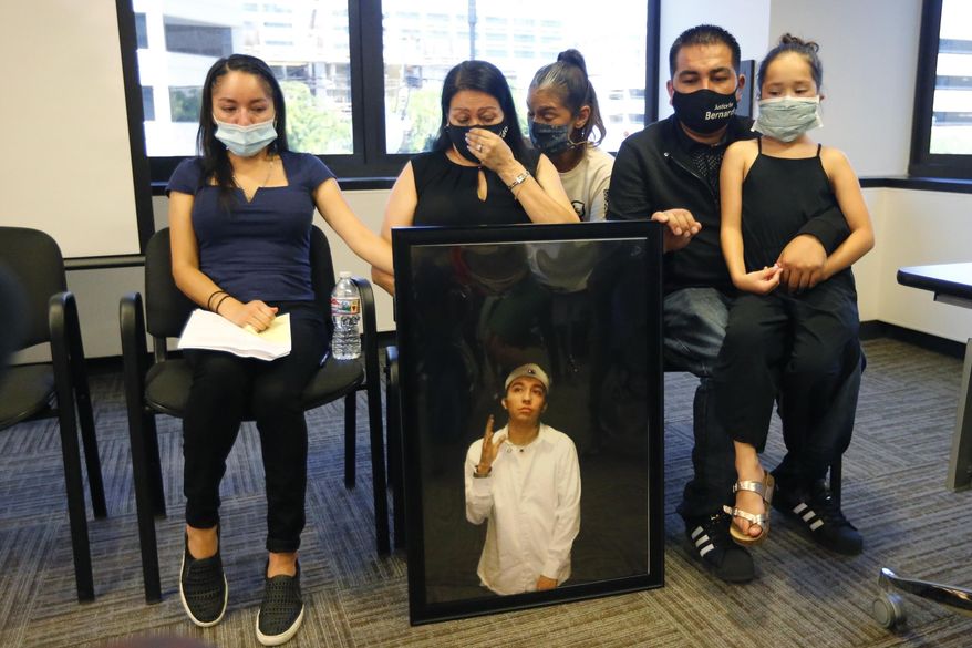 FILE - In this Thursday, July 9, 2020, file photo, Lucy Carbajal, center left, sits behind a photograph of her son Bernardo Palacios-Carbajal while other family members look on during a news conference at their attorney's office in Salt Lake City. District Attorney Sim Gill says Utah police officers were legally justified in firing more than 30 times and killing an armed man as he ran away. The case has become a rallying point for protesters in the state amid a national wave of dissent against police brutality. Gill said 22-year-old Bernardo Palacios-Carbajal was shot as he ran from Salt Lake City police officers who were investigating a gun-threat call and had yelled for him to drop a gun. The family of a Utah man who was killed and shot at more than 30 times as he ran from police filed a lawsuit against the Salt Lake City police department Friday, Sept. 25, 2020. (AP Photo/Rick Bowmer, File)