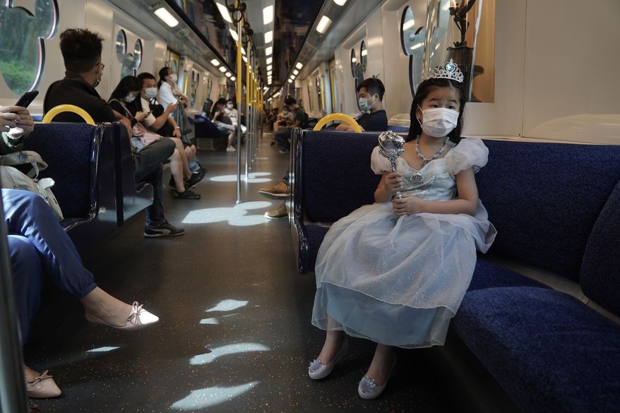 A visitor wearing a face mask rides on a train towards the Hong Kong Disneyland, Friday, Sept. 25, 2020. Hong Kong Disneyland reopened its doors to visitors after closed temporarily due to the coronavirus outbreak. (AP Photo/Kin Cheung)