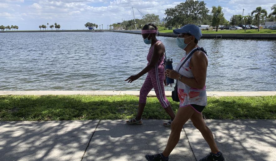 Eva Johnson, left, and Liz Cillo walk along the waterfront in St. Petersburg, Fla., Wednesday, Sept. 23, 2020. Trump recently said that COVID-19 was seriously affecting “virtually nobody” under the age of 18 and sought to frame the pandemic as largely impacting older Americans, as he argued for school districts to resume in-person learning. “We’re dispensable. We’re old. I feel as though he’s never showed any empathy or compassion toward us,” Cillo said. (AP Photo/Tamara Lush)