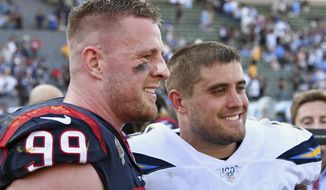FILE - In this Sept. 22, 2019 file photo, Houston Texans defensive end J.J. Watt (99) stands on the field next to his brother San Diego Chargers fullback Derek Watt (34) after the Texans defeated the Los Angeles Chargers 27 to 20 in an NFL game in Carson, Calif.  The three Watt brothers will share the field for the first time ever on Sunday, Sept. 27, 2020,  when J.J. Watt and the Texans visit T.J., Derek and the Pittsburgh Steelers. (AP Photo/John Cordes, File)