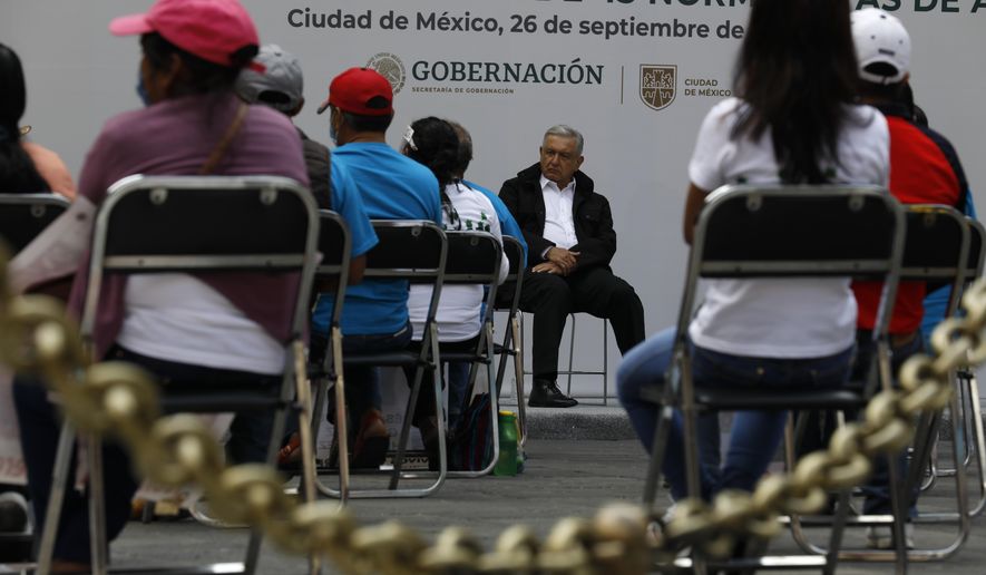 Mexico's President Andres Manuel Lopez Obrador, center, and family members of 43 missing students from the Rural Normal School of Ayotzinapa, listen to an update to the ongoing investigations on the sixth anniversary of the students' disappearance, at the National Palace in Mexico City, Saturday, Sept. 26, 2020. (AP Photo/Rebecca Blackwell)