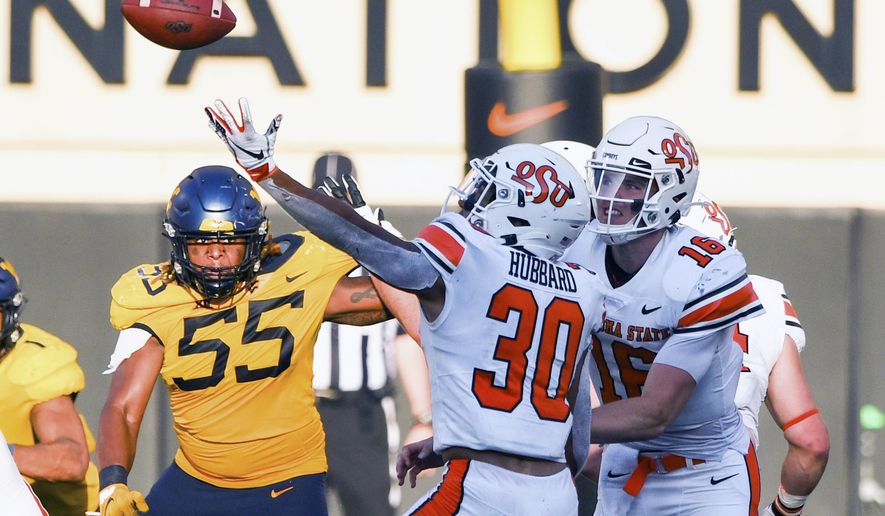 West Virginia defensive lineman Dante Stills (55) and Oklahoma State quarterback Shane Illingworth (16) watch as Oklahoma State running back Chuba Hubbard (30) tries to catch a bad snap during an NCAA college football game Saturday, Sept. 26, 2020, in Stillwater, Okla. (AP Photo/Brody Schmidt)
