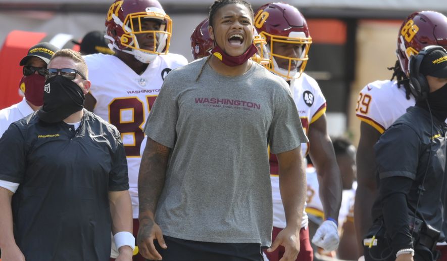 Washington Football Team defensive end Chase Young, center, watches from the sideline during the second half of an NFL football game against the Cleveland Browns, Sunday, Sept. 27, 2020, in Cleveland. (AP Photo/David Richard)