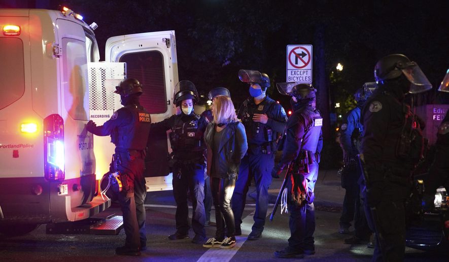 In this file photo, a female protester is loaded into a van after being arrested while rallying at the Mark O. Hatfield United States Courthouse on Saturday, Sept. 26, 2020, in Portland, Ore. A Harvard poll released Oct. 1 suggests Americans are open to President Trump&#39;s law-and-order campaign message. (AP Photo/Allison Dinner)
