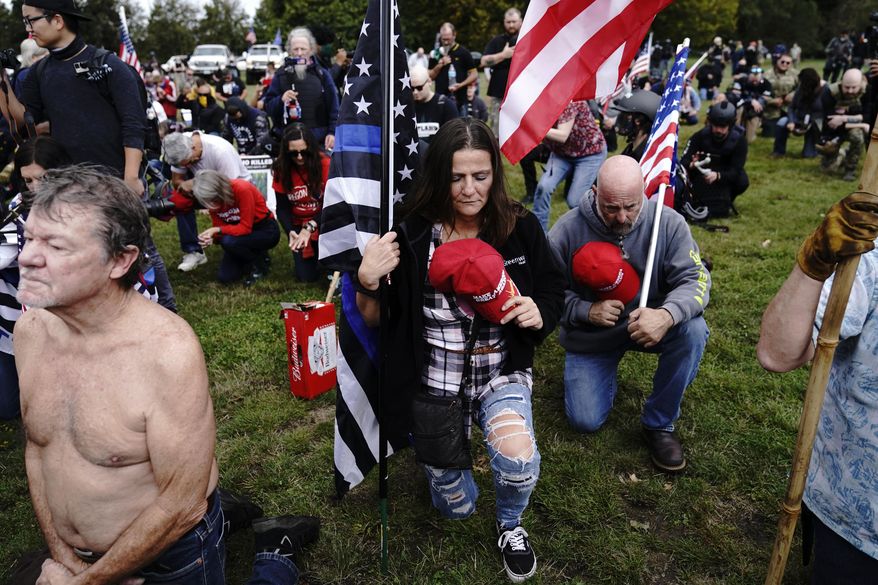 Members of the Proud Boys and other right-wing demonstrators kneel in prayer at a rally on Saturday, Sept. 26, 2020, in Portland, Ore. (AP Photo/John Locher)