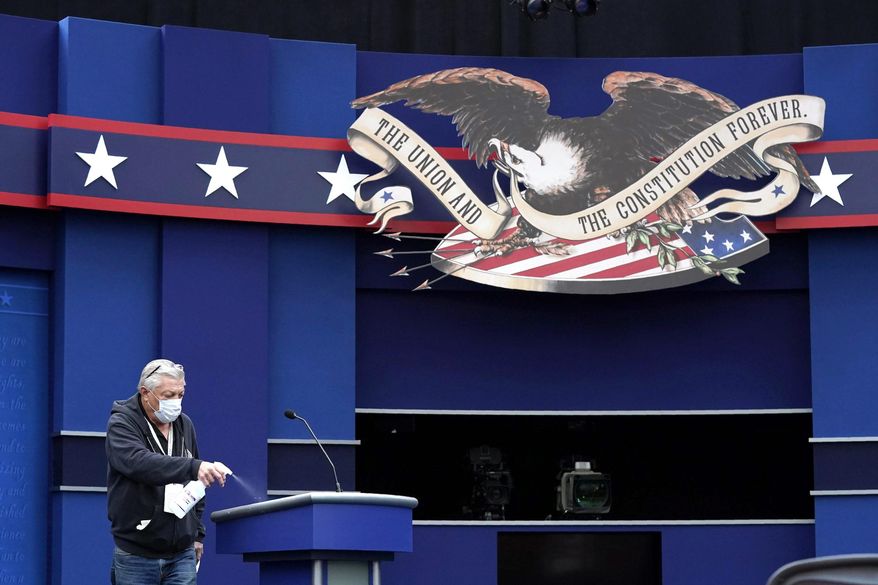 A worker sprays sanitizer on a lectern as preparations take place for the first presidential debate in Cleveland. (Associated Press)