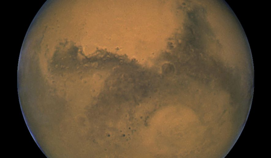 This Aug. 26, 2003 image made available by NASA shows Mars as it lines up with the Sun and the Earth. Photographed by the Hubble Space Telescope, it was about 55.8 million kilometers (34.6 million miles) from Earth. A network of salty ponds may be gurgling beneath Mars’ South Pole alongside a large underground lake, raising the prospect of tiny, swimming Martian life. Italian scientists reported their findings Monday, Sept. 28, 2020 two years after identifying what they believed to be a large subglacial lake. (J. Bell/NASA via AP)