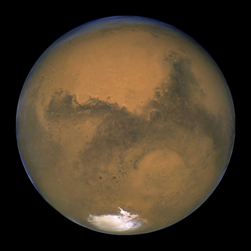 This Aug. 26, 2003 image made available by NASA shows Mars as it lines up with the Sun and the Earth. Photographed by the Hubble Space Telescope, it was about 55.8 million kilometers (34.6 million miles) from Earth. A network of salty ponds may be gurgling beneath Mars’ South Pole alongside a large underground lake, raising the prospect of tiny, swimming Martian life. Italian scientists reported their findings Monday, Sept. 28, 2020 two years after identifying what they believed to be a large subglacial lake. (J. Bell/NASA via AP)