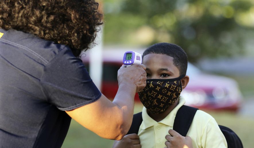 FILE - In this Monday, Aug. 24, 2020, file photo, fifth-grader Marcques Haley, 10, gets his temperature checked by school nurse Rachel White before entering Stephens Elementary School in Little Rock, Ark. The Little Rock teachers union said Sunday, Sept. 27, 2020, that its members won't show up for in-person classes due to concerns about the spread of coronavirus in schools. (Tommy Metthe/The Arkansas Democrat-Gazette via AP, File)