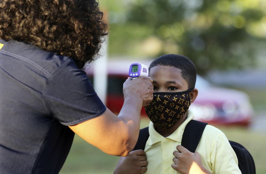 FILE - In this Monday, Aug. 24, 2020, file photo, fifth-grader Marcques Haley, 10, gets his temperature checked by school nurse Rachel White before entering Stephens Elementary School in Little Rock, Ark. The Little Rock teachers union said Sunday, Sept. 27, 2020, that its members won't show up for in-person classes due to concerns about the spread of coronavirus in schools. (Tommy Metthe/The Arkansas Democrat-Gazette via AP, File)