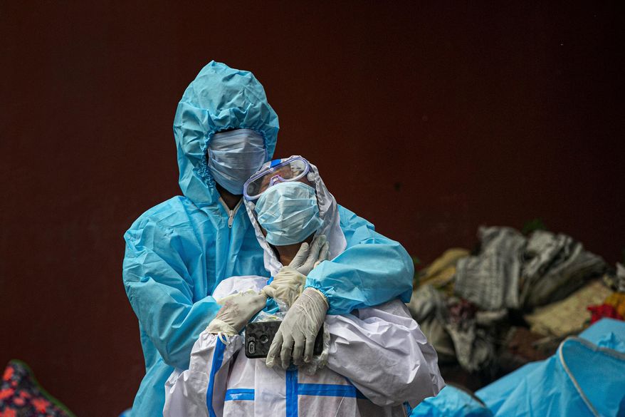 FILE - In this Sept. 10, 2020, file photo, a woman wearing white protective gear, foreground, mourns after taking a glimpse of her husband's body, a victim of COVID 19, at a cremation site in Gauhati, India. The worldwide death toll from the coronavirus eclipsed 1 million, nine months into a crisis that has devastated the global economy, tested world leaders' resolve, pitted science against politics and forced multitudes to change the way they live, learn and work. (AP Photo/Anupam Nath, File)