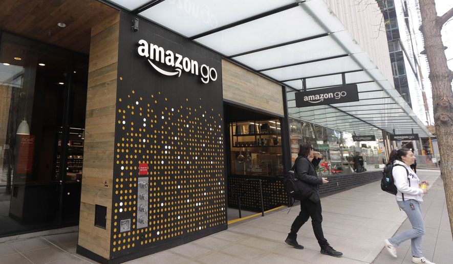 FILE - In this March 4, 2020 file photo, people walk out of an Amazon Go store, in Seattle. Amazon is rolling out a new device for contactless transactions that will scan an individual’s palm. The Amazon One, which will initially launch in two Amazon Go stores in Seattle, is being viewed as a way for people to use their palm to make everyday activities like paying at a store easier. (AP Photo/Ted S. Warren, File)