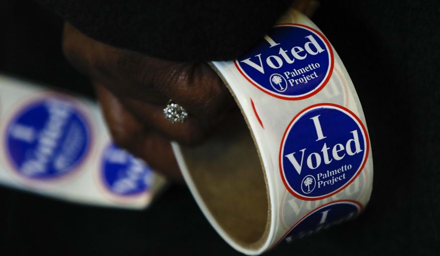 A worker holds stickers at a polling place for the South Carolina primary election, Saturday, Feb. 29, 2020, in Columbia, S.C. (AP Photo/Matt Rourke)