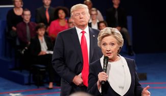 Democratic presidential nominee Hillary Clinton, right, speaks as Republican presidential nominee Donald Trump listens during the second presidential debate at Washington University in St. Louis, Sunday, Oct. 9, 2016. Stunned Republicans demanded answers Sunday after an explosive court filing linked the 2016 Hillary Clinton campaign to a purported surveillance operation aimed at digging up dirt on Donald Trump both before and after he won the presidential election. (Rick T. Wilking/Pool via AP) **FILE**