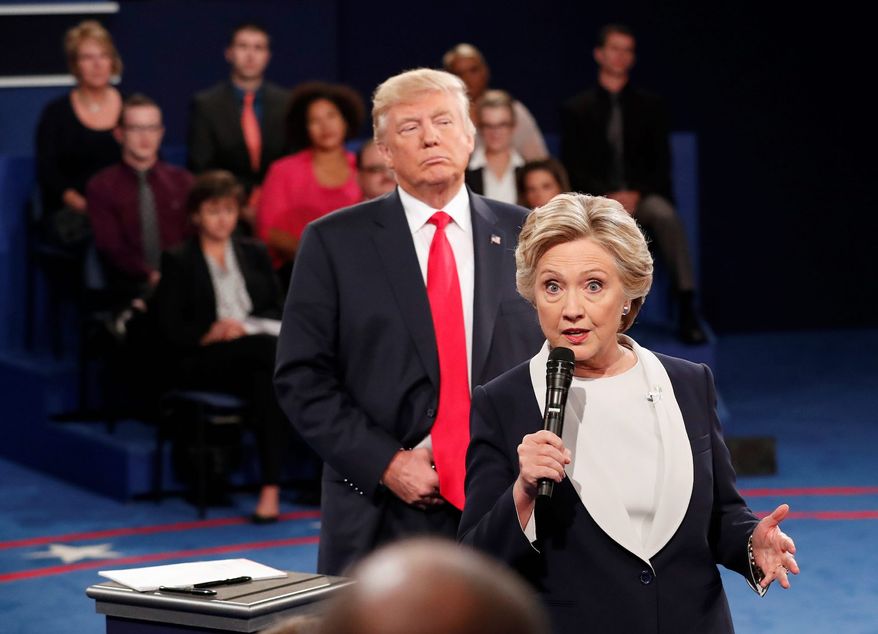 Democratic presidential nominee Hillary Clinton, right, speaks as Republican presidential nominee Donald Trump listens during the second presidential debate at Washington University in St. Louis, Sunday, Oct. 9, 2016. Stunned Republicans demanded answers Sunday after an explosive court filing linked the 2016 Hillary Clinton campaign to a purported surveillance operation aimed at digging up dirt on Donald Trump both before and after he won the presidential election. (Rick T. Wilking/Pool via AP) **FILE**