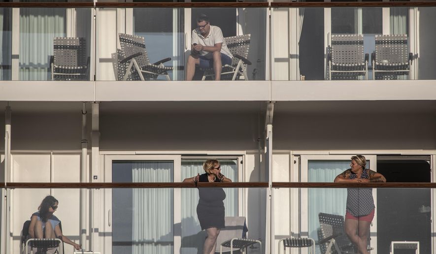 Passengers of the Mein Schiff 6 cruise ship stand outside their cabins as the ship is docked at Piraeus port, near Athens on Tuesday, Sept. 29, 2020. Greek authorities say 12 crew members on a Maltese-flagged cruise ship carrying more than 1,500 people on a Greek islands tour have tested positive for coronavirus and have been isolated on board.(AP Photo/Petros Giannakouris)