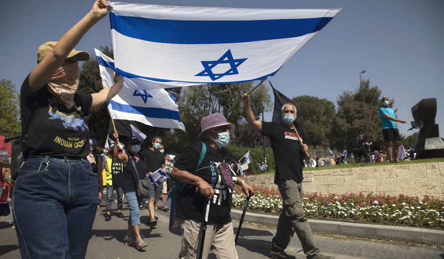 Israeli protesters wave flags and chant slogans during a demonstration against a proposed measure to curtail public demonstrations during the current nationwide lockdown due to the coronavirus pandemic, in front of the Knesset, Israel's parliament in Jerusalem, Tuesday, Sept. 29, 2020. (AP Photo/Sebastian Scheiner)