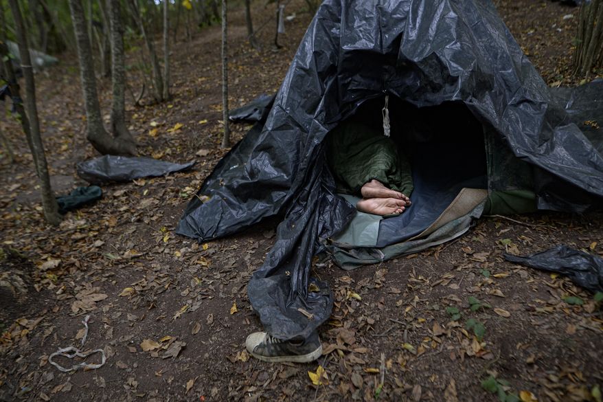 FILE - In this Friday, Sept. 25, 2020 file photo, a migrant rests in a tent improvised from plastic sheets at a makeshift camp in a forest outside Velika Kladusa, Bosnia. Bosnian authorities have started emptying U.N.-run migrant camps in town centers housing hundreds of people, moving residents to a crowded, out-of-the-way facility that’s not equipped for winter conditions — or just leaving them to fend for themselves in the woods. (AP Photo/Kemal Softic, File)