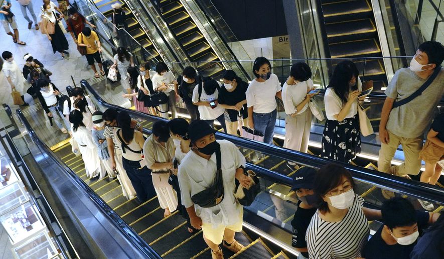 People take elevators at a shopping building in Tokyo on Aug. 24, 2020. Japanese manufacturers’ sentiments improved for the first time in three years, a quarterly Bank of Japan survey showed Thursday, Oct. 1, 2020, as the nation grappled with stagnation worsened by the coronavirus pandemic. (AP Photo/Eugene Hoshiko)