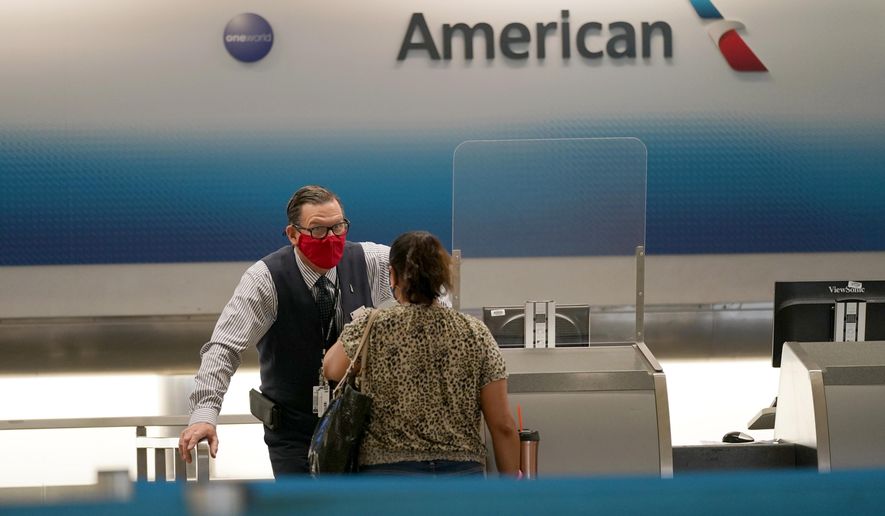 American Airlines ticket agent Henry Gemdron, left, works with a customer at Miami International Airport during the coronavirus pandemic, Wednesday, Sept. 30, 2020, in Miami. The airline industry has been decimated by the pandemic. The Payroll Support Program given to the airlines as part of the CARES Act runs out Thursday. (AP Photo/Lynne Sladky)