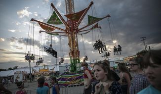 People wait to ride a revolving swing at the Perry State Fair in New Lexington, Ohio, Friday, July 24, 2020. In the towns that speckle the Appalachian foothills of southeast Ohio, the pandemic has barely been felt. Coronavirus deaths and racial protests _ events that have defined 2020 nationwide _ are mostly just images on TV from a distant America. (AP Photo/Wong Maye-E)