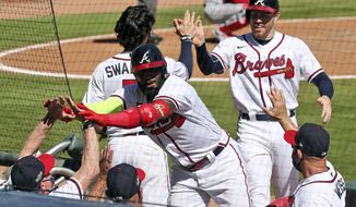 Atlanta Braves&#x27; Marcell Ozuna, center, is greeted at the dugout after hitting a two-run home run in the eighth inning against the Cincinnati Reds in Game 2 of a National League wild-card baseball series, Thursday, Oct. 1, 2020, in Atlanta. (Curtis Compton/Atlanta Journal-Constitution via AP)