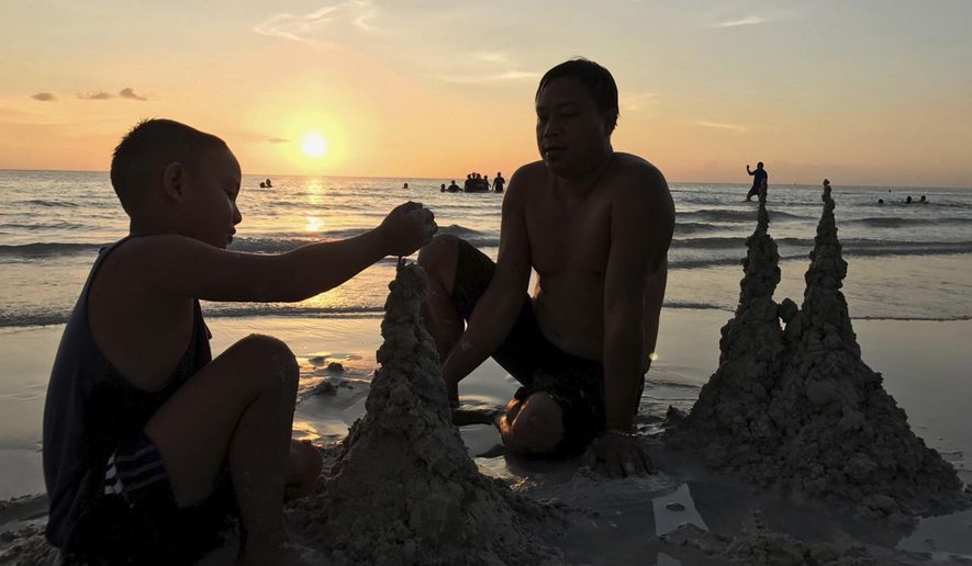 FILE - In this Oct. 26, 2018, file photo, a father and his son create sand formations on the beach during sunset in Boracay island, Philippines. Two of the most popular Philippine tourist destinations, including Boracay beach, have partially reopened, Friday, Oct. 2, 2020, drawing only a fraction of their usual huge crowds given continuing coronavirus restrictions. (AP Photo/Joeal Calupitan, File)