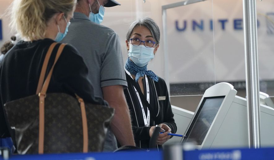 Travellers check in at a United Airlines kiosk with help from a United employee in the main terminal of Denver International Airport Thursday, Oct. 1, 2020, in Denver. (AP Photo/David Zalubowski)