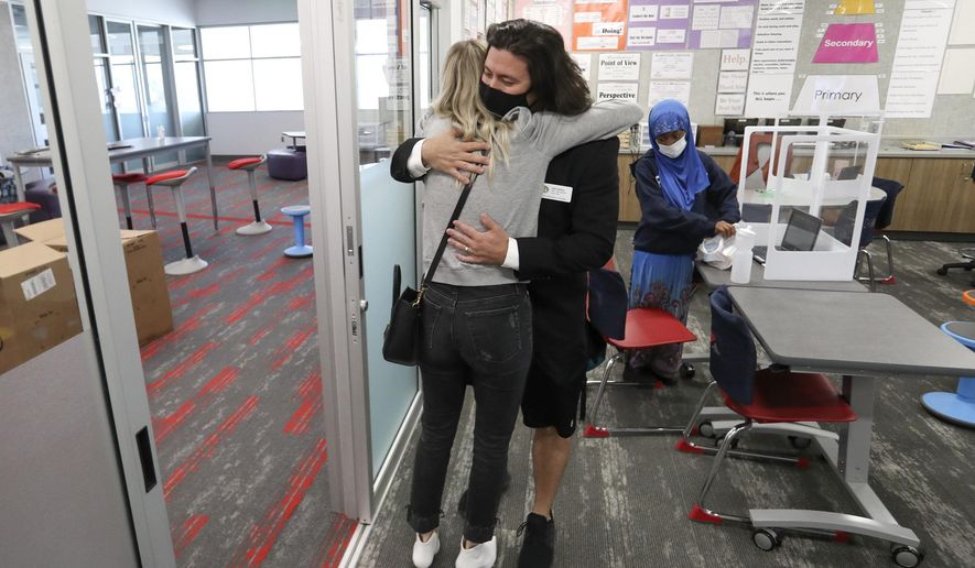John Arthur, Utah's Teacher of the Year, hugs his wife, Stacey, in his classroom at Meadowlark Elementary School in Salt Lake City after learning of the award on Thursday, Oct. 1, 2020. Now in his eighth year of teaching, Arthur teaches sixth grade at Meadowlark Elementary School, a Title I school in the Salt Lake City School District. It is there that he pays it forward, helping his students learn to advocate for children and immigrants through music videos that they produce together and share on their YouTube channel, 9thEvermore. Arthur’s students have received national recognition for their work. (Steve Griffin/The Deseret News via AP)