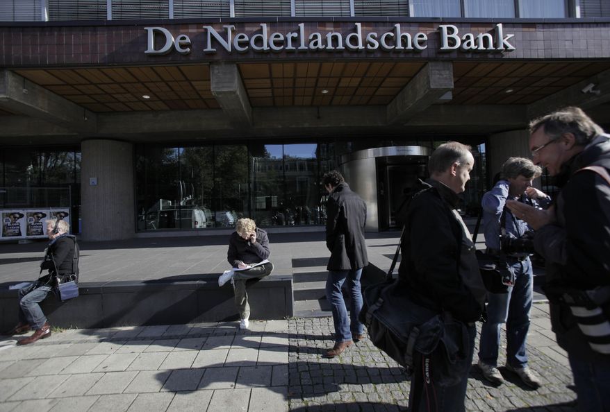 FILE - IN this Monday, Oct. 12, 2009 file photo, reporters wait outside the De Nederlandsche Bank, the Dutch national bank, in Amsterdam, Netherlands. The Netherlands’ central bank has moved its Dutch-based stock of gold from its headquarters in Amsterdam to a safe in the nearby city of Haarlem. The 14,000 bars and about 1,000 boxes of gold coins worth a total of some 10 billion euros ($11.7 billion) were transported in a meticulously and closely guarded operation that ended Saturday, Oct. 3, 2020. (AP Photo/Peter Dejong, File)