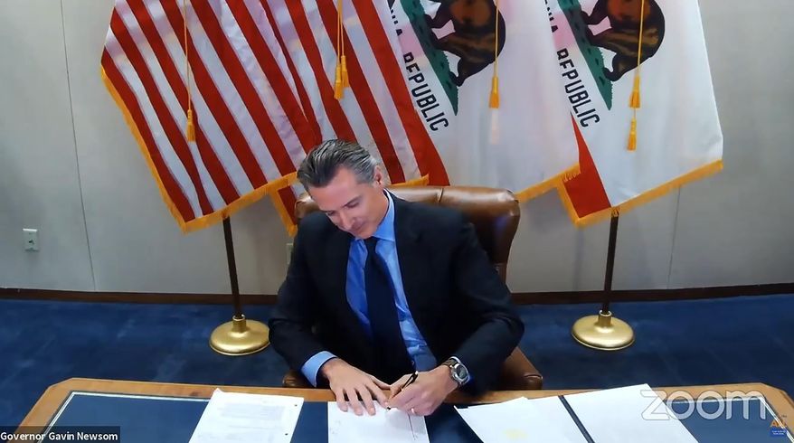 FILE - In this Wednesday, Sept. 30, 2020 file image made from video from the Office of the Governor, California Gov. Gavin Newsom signs into law a bill that establishes a task force to come up with recommendations on how to give reparations to Black Americans in Sacramento, Calif. A conservative legal group announced Monday, Oct. 5 that it sued to block California's first-in-the-nation law that requires hundreds of corporations based in the state to have directors from racial or sexual minorities on their boards. (Office of the Governor via AP, File)