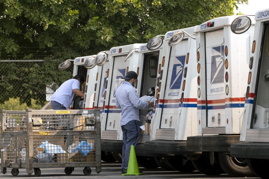 FILE - In this Aug. 20, 2020 file photo, postal workers load their mail delivery vehicles at the Panorama city post office in Los Angeles. The Nov. 3 election will test California's commitment to voting by mail as the nation's most populous state will offer fewer in-person polling places hoping it will convince more people to cast ballots from the safety of their mailboxes during a pandemic. If it doesn't work, the state could see long lines and frustrated voters on Election Day compounded by coronavirus protocols that will make voting in person slower in a year expected to draw a big turnout. (AP Photo/Richard Vogel, File)