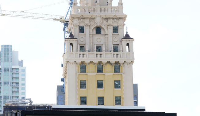 A flashing sign reads, "Make Miami Count," near the iconic "Freedom Tower," Monday, Oct. 5, 2020, in downtown Miami. (AP Photo/Wilfredo Lee)