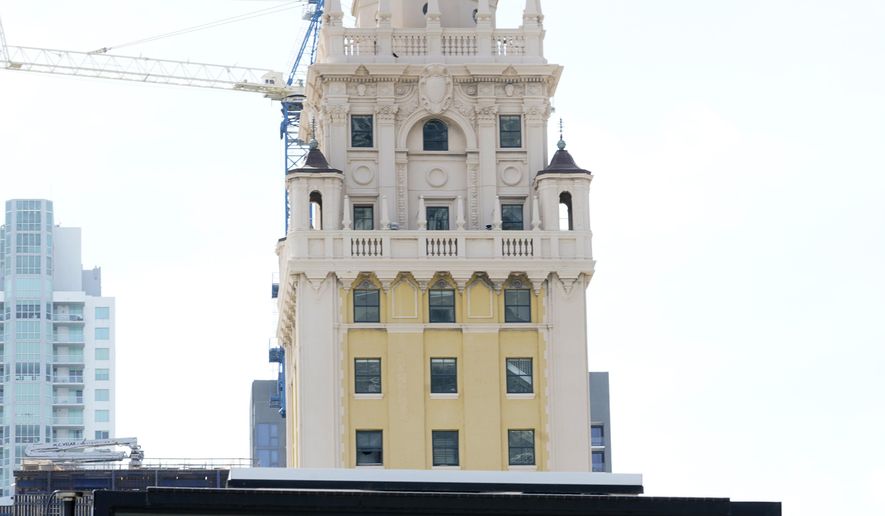 A flashing sign reads, "Make Miami Count," near the iconic "Freedom Tower," Monday, Oct. 5, 2020, in downtown Miami. (AP Photo/Wilfredo Lee)