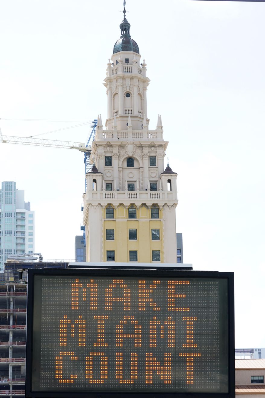 A flashing sign reads, "Make Miami Count," near the iconic "Freedom Tower," Monday, Oct. 5, 2020, in downtown Miami. (AP Photo/Wilfredo Lee)