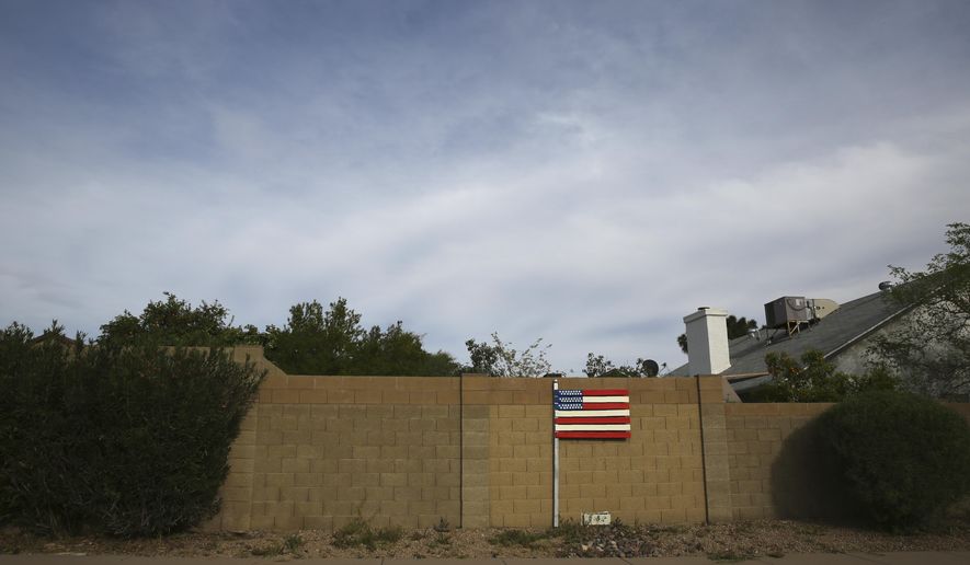 A makeshift U.S. flag stands behind a home located near the intersection between the Arizona State Route 101 and the Interstate 17 freeway in Phoenix, Ariz., on March 9, 2020. America's suburbs are poised to decide not just who wins the White House this year -- but the contours of the debate over guns, immigration, work, schools, housing and health care for years to come. What makes the suburbs matter is that they sit between the density of cities that favor Democrats and the open land of rural towns that back Republicans. (AP Photo/Dario Lopez-MIlls)