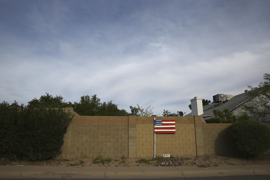A makeshift U.S. flag stands behind a home located near the intersection between the Arizona State Route 101 and the Interstate 17 freeway in Phoenix, Ariz., on March 9, 2020. America's suburbs are poised to decide not just who wins the White House this year -- but the contours of the debate over guns, immigration, work, schools, housing and health care for years to come. What makes the suburbs matter is that they sit between the density of cities that favor Democrats and the open land of rural towns that back Republicans. (AP Photo/Dario Lopez-MIlls)