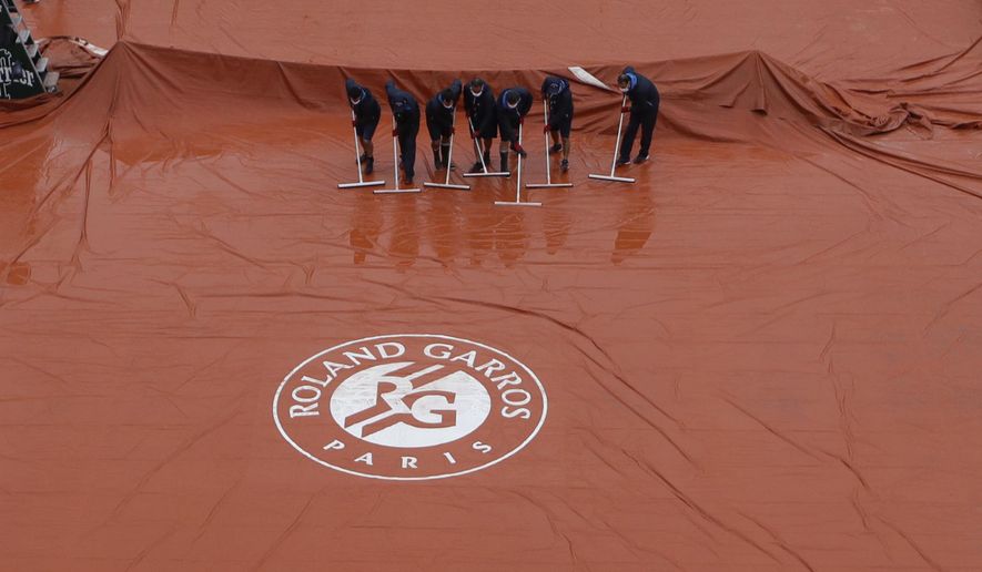 Stadium workers remove rain water from the cover of Suzanne Lenglen court as rain delayed fourth round matches of the French Open tennis tournament at the Roland Garros stadium in Paris, France, Monday, Oct. 5, 2020. (AP Photo/Alessandra Tarantino)