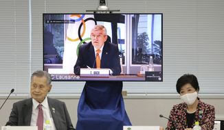 In this Sept. 24, 2020, file photo, IOC President Thomas Bach, on the screen, speaks remotely with Tokyo 2020 Organizing Committee President Yoshiro Mori, left, and Tokyo Gov. Yuriko Koike, right, during an on-line meeting focused on how to pull off the delayed Tokyo Games, in Tokyo. The IOC and local organizers are trying to “simplify” next year&#39;s postponed Tokyo Olympics, promising to save money in what one study says is already the most expensive Summer Olympics on record. (Du Xiaoyi/Pool Photo via AP)