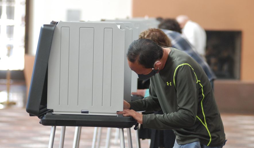 Will Halm, foreground, joins a steady stream of voters to participate in the first day of balloting in New Mexico, at the Santa Fe Convention Center on Tuesday, Oct. 6, 2020, in Santa Fe. Halm said he voted in-person and early to ensure his ballot counts and avoid crowds as a safety precaution against COVID-19. Election officials are witnessing a massive surge in absentee ballot requests. (AP Photo/Morgan Lee)