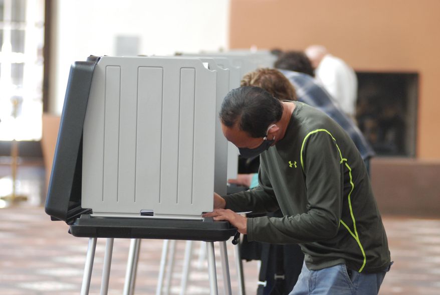 Will Halm, foreground, joins a steady stream of voters to participate in the first day of balloting in New Mexico, at the Santa Fe Convention Center on Tuesday, Oct. 6, 2020, in Santa Fe. Halm said he voted in-person and early to ensure his ballot counts and avoid crowds as a safety precaution against COVID-19. Election officials are witnessing a massive surge in absentee ballot requests. (AP Photo/Morgan Lee)