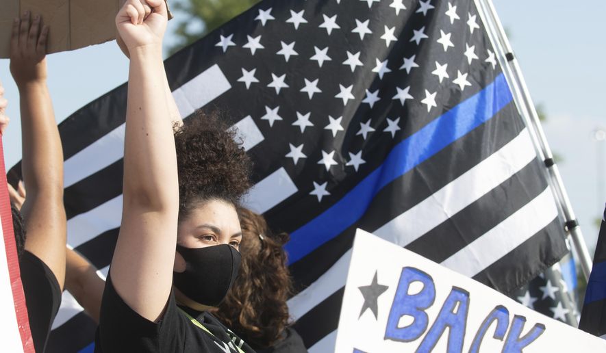 A Black Lives Matter supporter raises her fist in solidarity amid a crowd of "Back the Blue" supporters in Topeka, Kan., Aug. 25., 2020. Some advocates in Topeka see long-standing tensions between the police and the city's 125,000 residents, particularly minorities. But advocates of change have been met by vocal support for the police. (Evert Nelson/The Topeka Capital-Journal via AP)